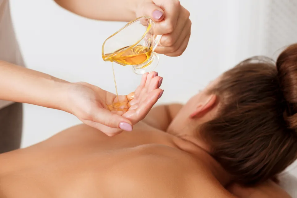 Massageöl wird zur Vorbereitung einer Rückenmassage in die Hand gegossen